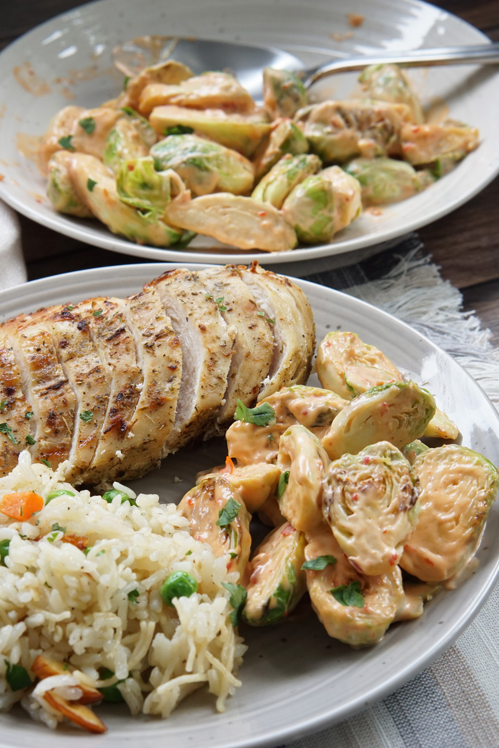 Bang bang brussels sprouts on a plate with rice pilaf and air fryer chicken breast