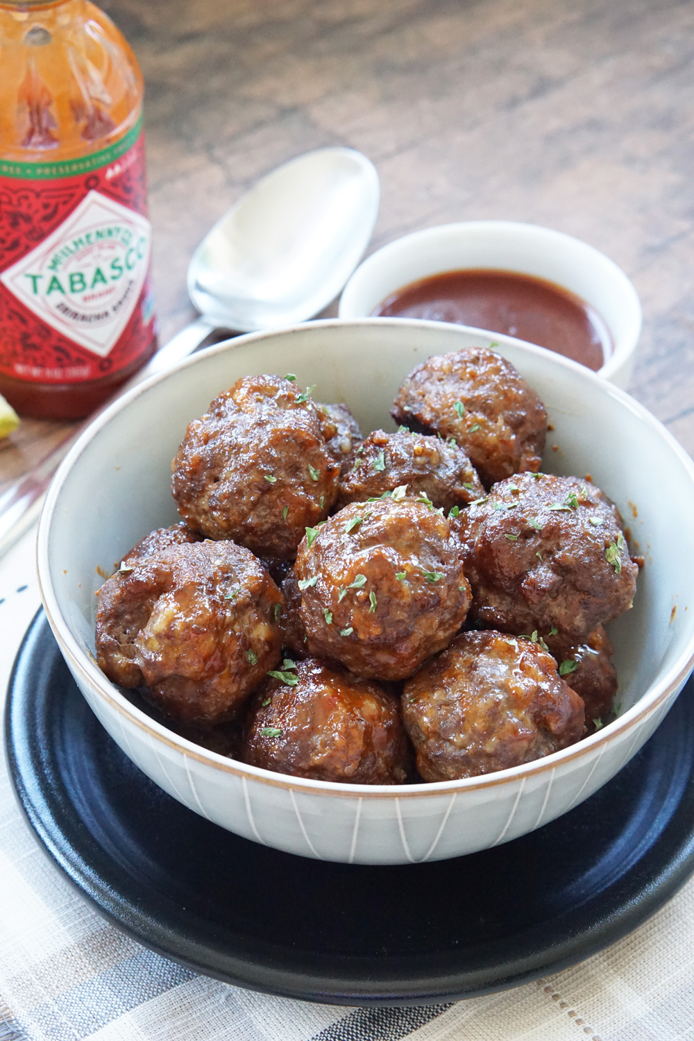 A bowl of honey sriracha meatballs with extra sauce for dipping.