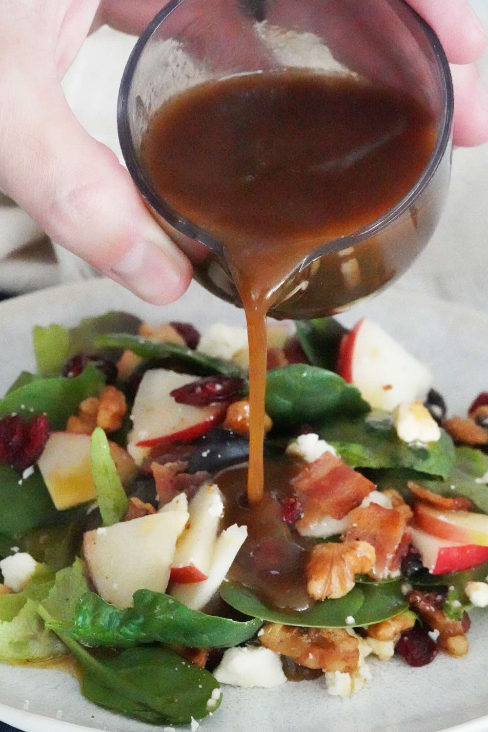 Pouring maple balsamic dressing over a salad